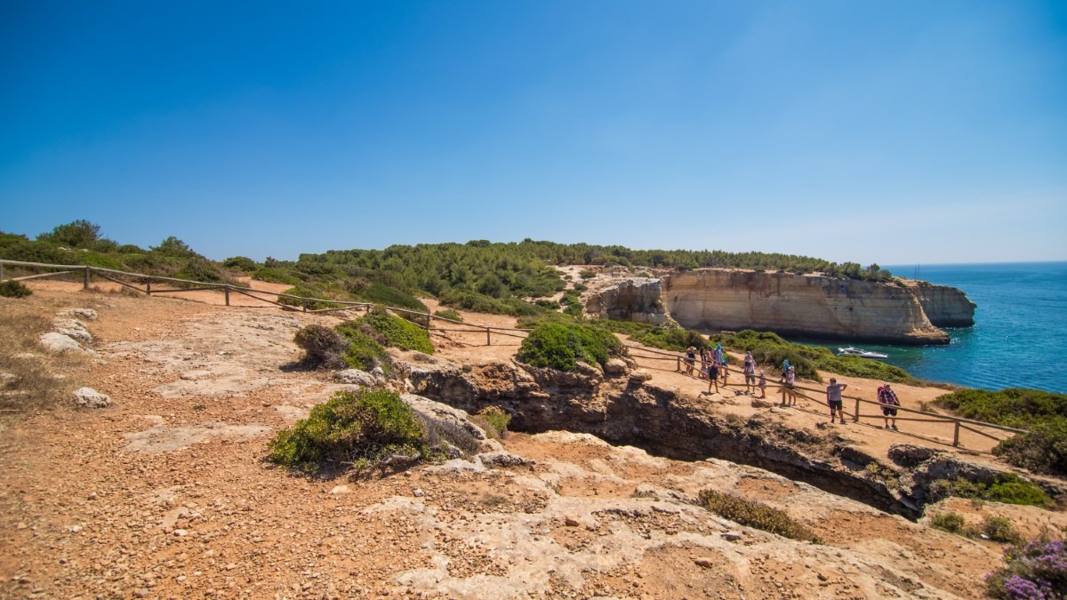 Falaises dorées en Algarve avec sentier côtier et océan.