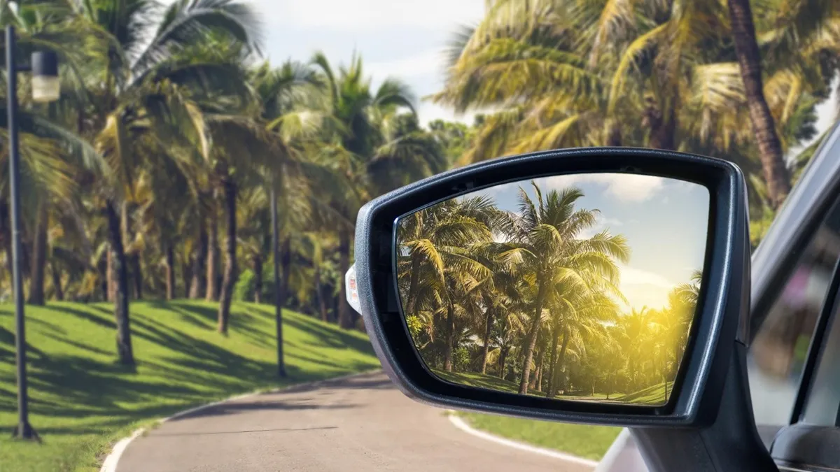 Voiture compacte circulant sur une route tropicale près de la mer